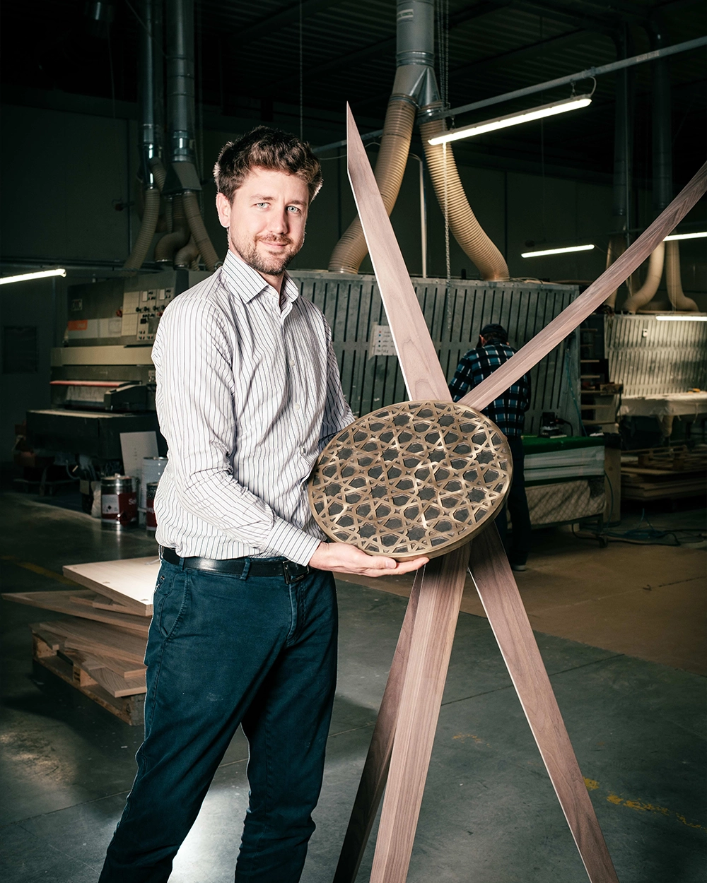 Chiodelli Arte designer holding a handcrafted geometric inlaid circular element in the luxury furniture atelier.