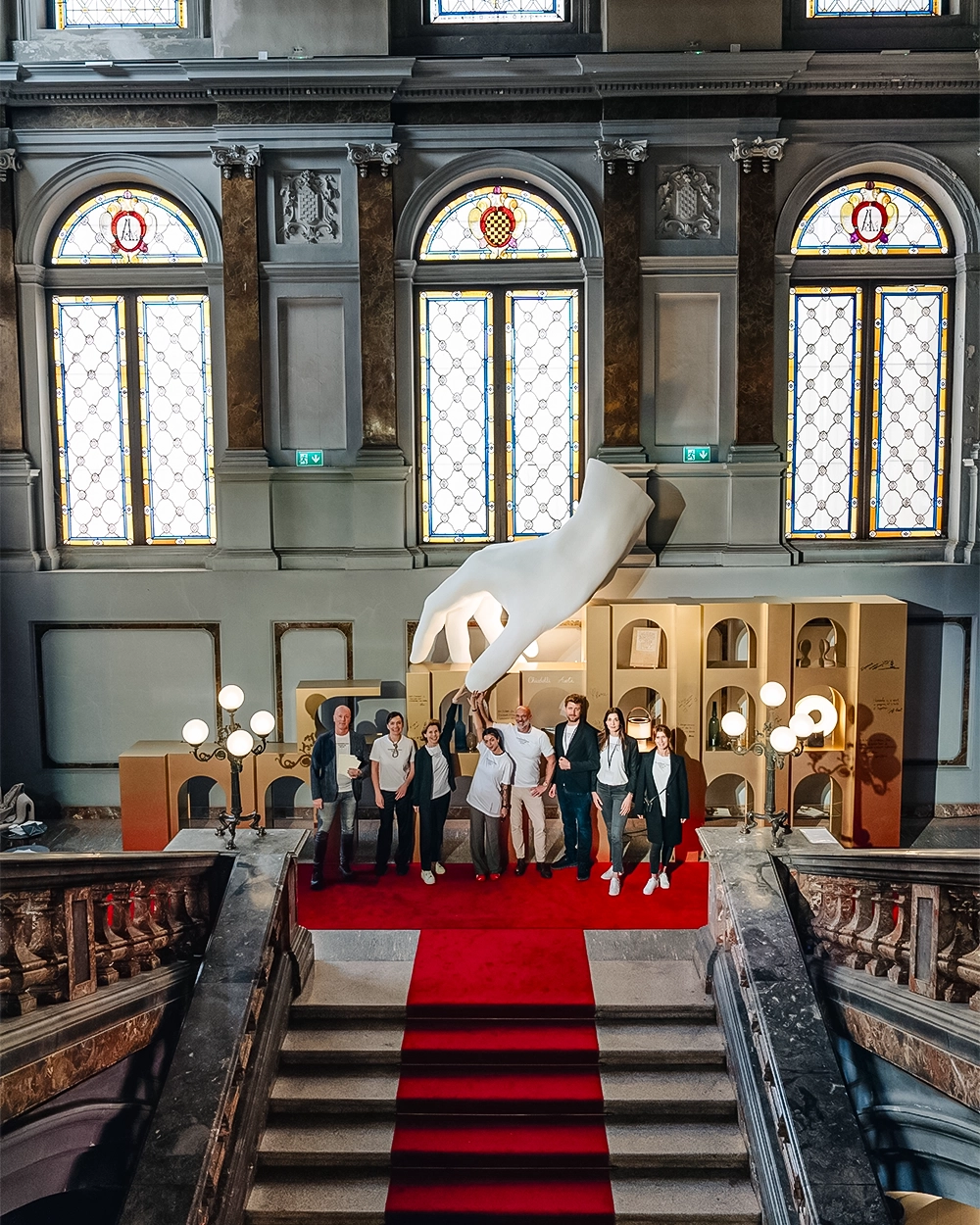 Chiodelli Arte team at Palazzo Litta during Milan Design Week in front of the hand sculpture and gold installation.